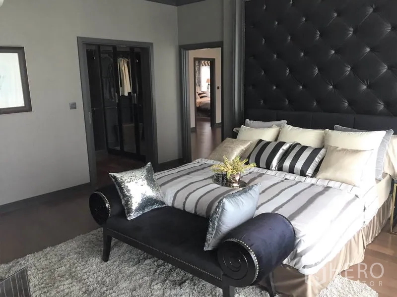 Detached House for rent or sale in Bang Kapi, Bangkok - Master bedroom with tufted headboard, bench and walk-in closet access.