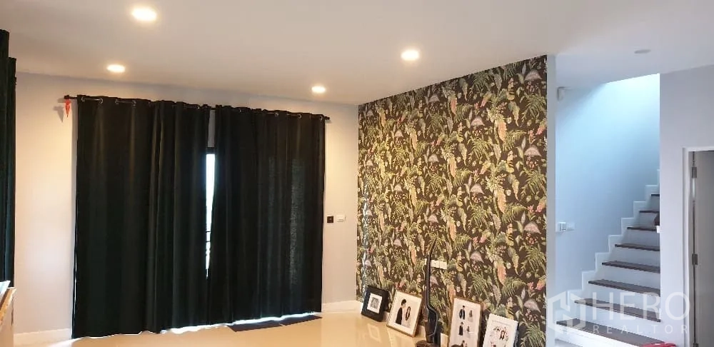 Detached House for rent or sale in Lam Luk Ka, Pathum Thani - Living room with floral feature wall and staircase to upper floor.