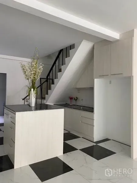 联排别墅 出租或出售在Khlong Toei, Bangkok - 白色厨房配黑色台面中岛与楼梯下收纳柜