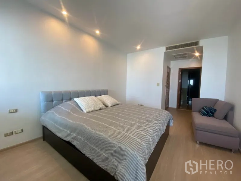 Condominium for rent in Sathon, Bangkok - Primary bedroom facing entry and ensuite, featuring a small sofa corner.