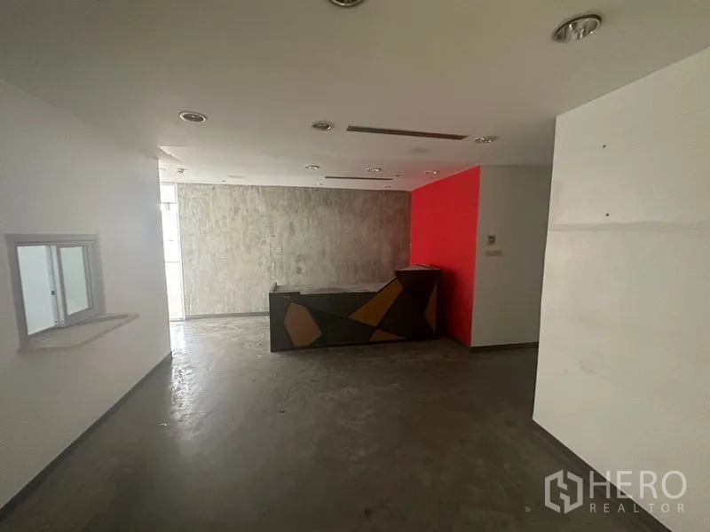 办公空间 出租在Khlong Toei, Bangkok - 接待大堂配几何造型前台与红色强调墙。