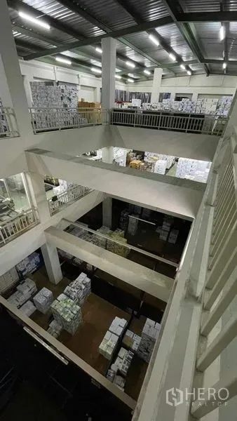 Warehouse for rent or sale in Bangkok Yai, Bangkok - Multi-level storage hall with high ceiling and stacked goods seen from mezzanine.