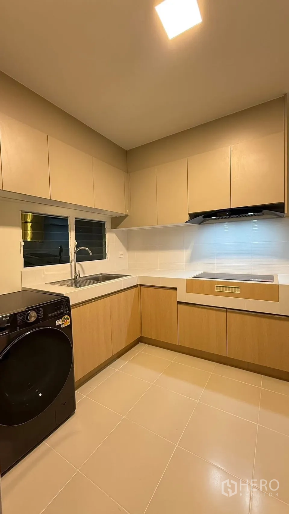 Detached House for rent in Bang Phli, Samut Prakan - L-shaped kitchen featuring induction hob, hood, sink, and ample storage.