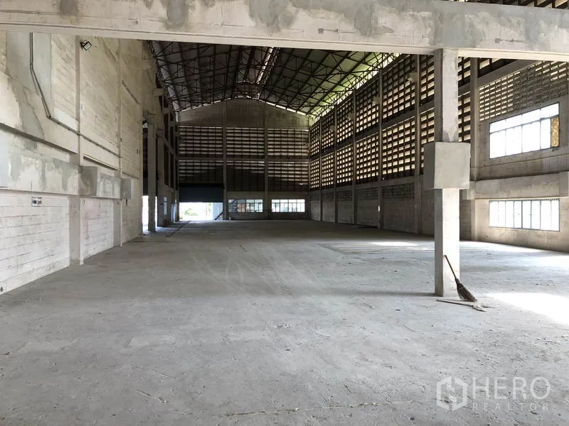 Factory for rent in Lam Luk Ka, Pathum Thani - Deep warehouse hall with concrete floor, ventilation blocks and a rear roller shutter.