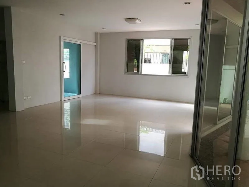 Detached House for rent in Phra Khanong, Bangkok - Bright living room with large windows and a sliding glass door to a sunroom.