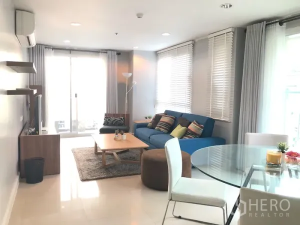 公寓 出租或出售在Khlong Toei, Bangkok - 客厅采光充足，蓝色沙发、玻璃餐桌及通向阳台的推拉门