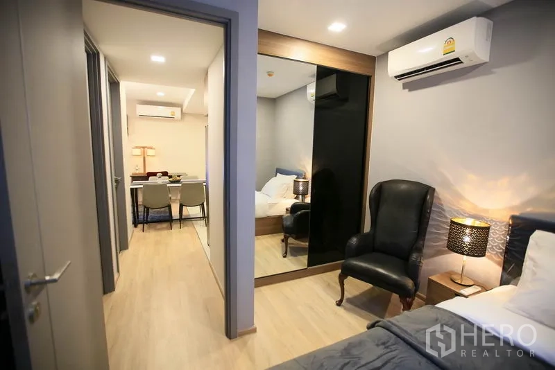 公寓 出租或出售在Watthana, Bangkok - 从次卧望向走廊，可见镜面衣柜与空调。