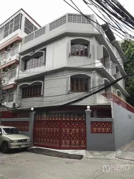 Home Office for rent in Dusit, Bangkok - Corner view of a three-storey home office with arched windows and a decorative red gate.