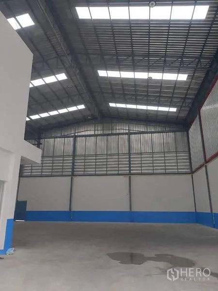 Warehouse for rent in Bang Phli, Samut Prakan - Interior bay showing a roller shutter door, insulated metal walls and skylights.