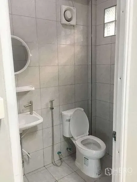 货栈 出租在Mueang Samut Prakan, Samut Prakan - 瓷砖卫生间，含坐便器、洗手盆、镜子与排气扇。