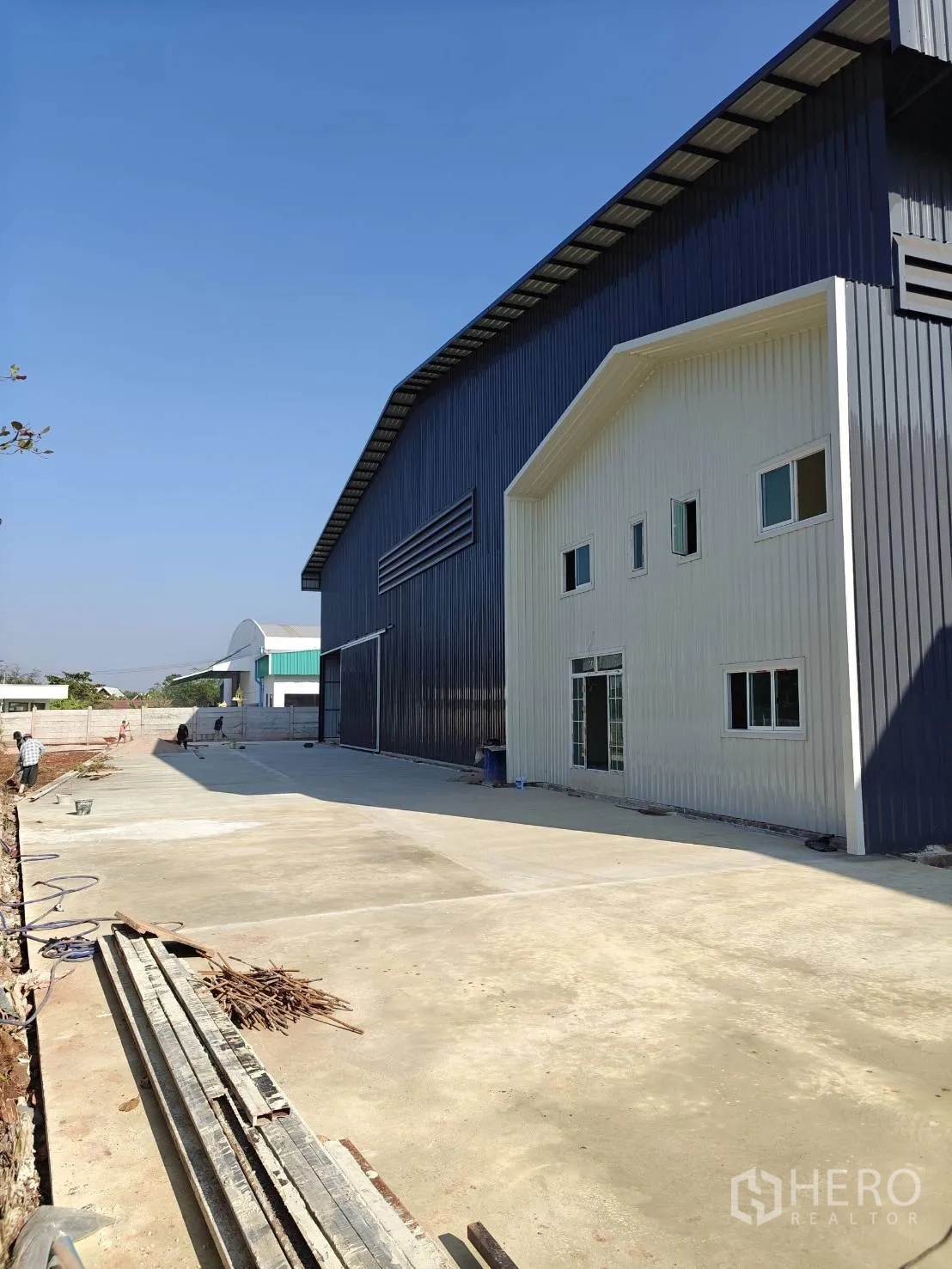 โรงงาน for rent in Mueang Samut Sakhon, Samut Sakhon - ภาพภายนอกอาคารโรงงานและส่วนออฟฟิศ พร้อมลานคอนกรีตกว้างเหมาะสำหรับรถบรรทุก.