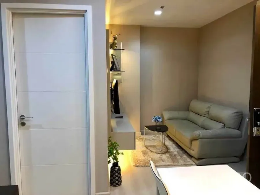 Condominium for rent or sale in Phaya Thai, Bangkok - Entrance view to the living area with sofa, TV wall and warm ambient lighting.