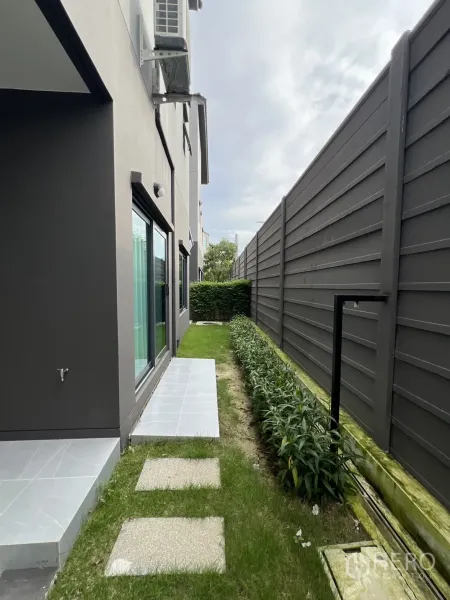 独立式住宅 出租在Prawet, Bangkok - 侧庭花园，踏步石与私密围墙旁的绿植。