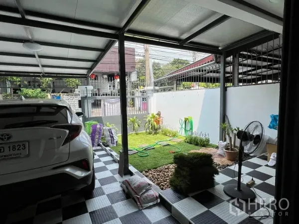 联排别墅 出租在Din Daeng, Bangkok - 带顶车位与黑白格地面，旁为小型前花园与大门。