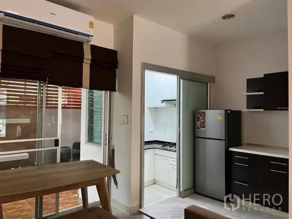 Townhouse for rent in Saphan Sung, Bangkok - Dining nook beside sliding doors and a separate kitchen with glass partition and stainless refrigerator.