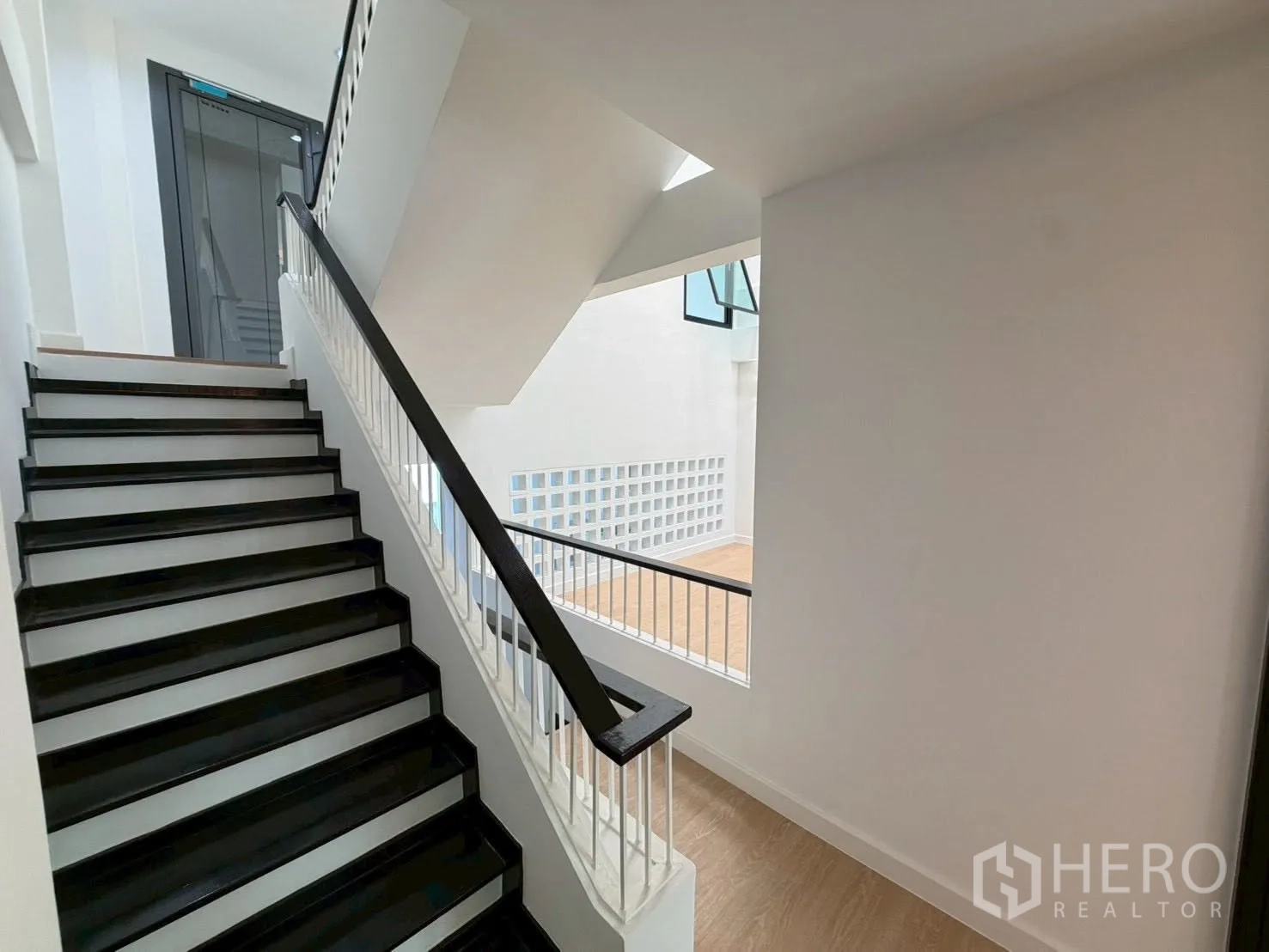 Townhouse for sale in Phra Khanong, Bangkok - Stair landing with black-and-white handrail and view to the elevator.