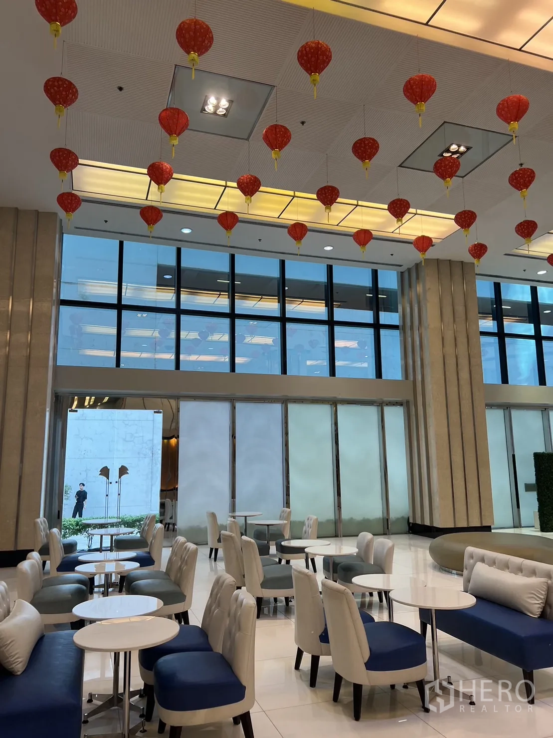 零售空间 出租在Khlong Toei, Bangkok - 明亮的零售大堂，配休闲座椅、圆桌、落地窗与悬挂的红色灯笼