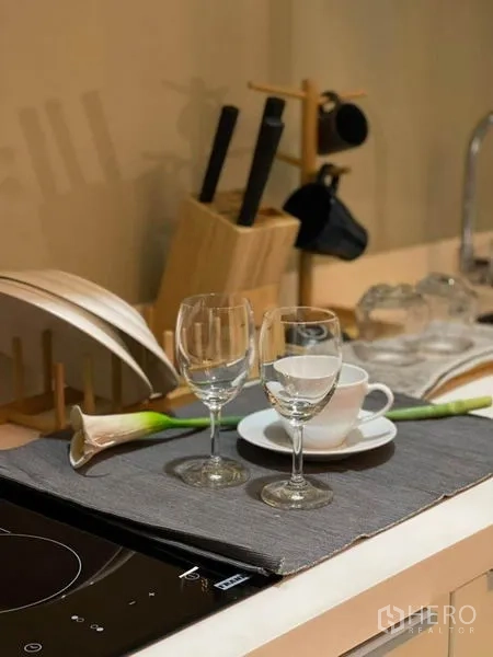 Condominium for rent in Ratchathewi, Bangkok - Close-up of kitchenette counter with induction hob, glassware and utensils.