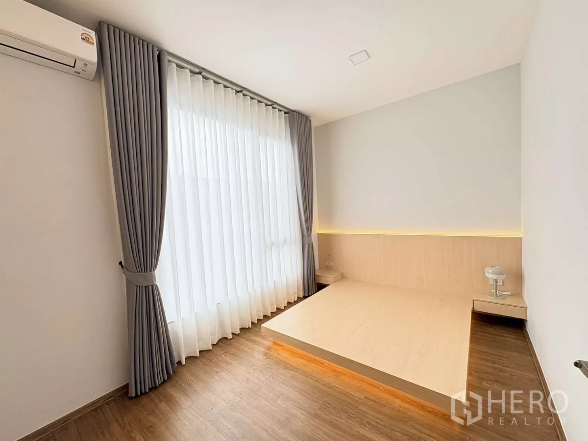 联排别墅 出租在Bang Phli, Samut Prakan - 卧室配平台床、灰色窗帘与壁挂空调。