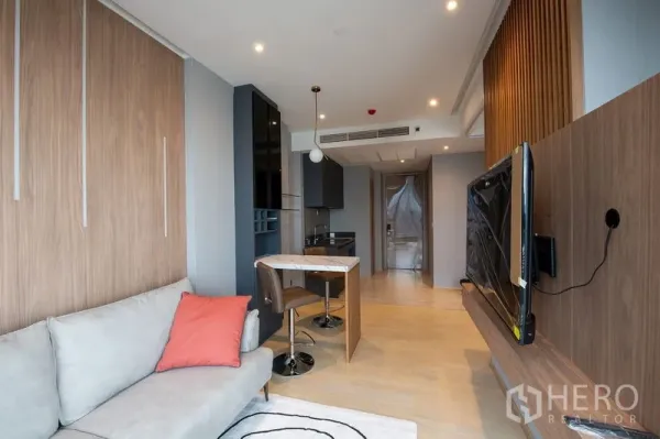 Condominium for rent in Din Daeng, Bangkok - Long view from living area toward entry with wall-mounted TV, light wood flooring and recessed lighting.