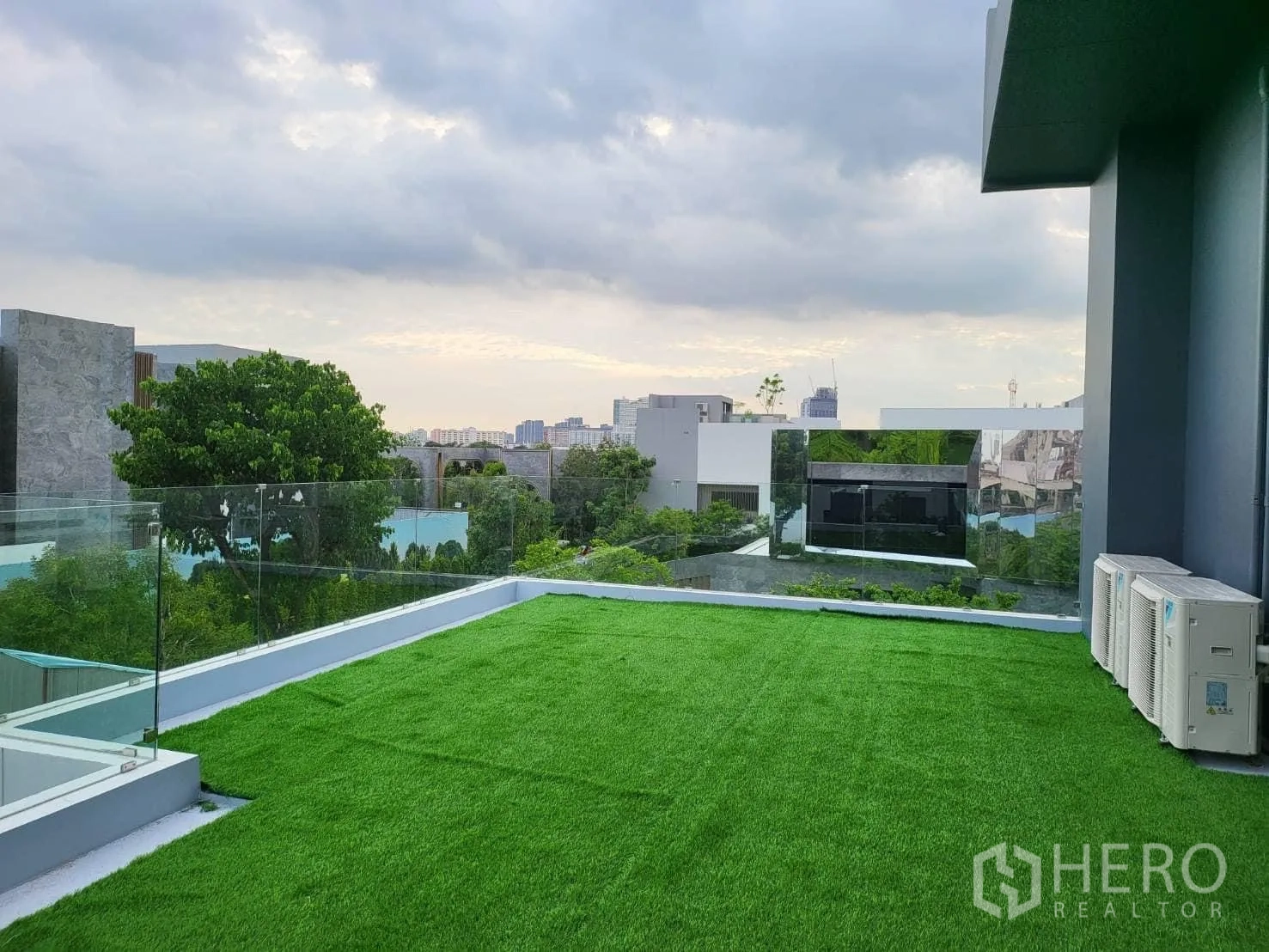 Detached House for rent - Rooftop terrace with artificial grass, glass railing and distant city views.