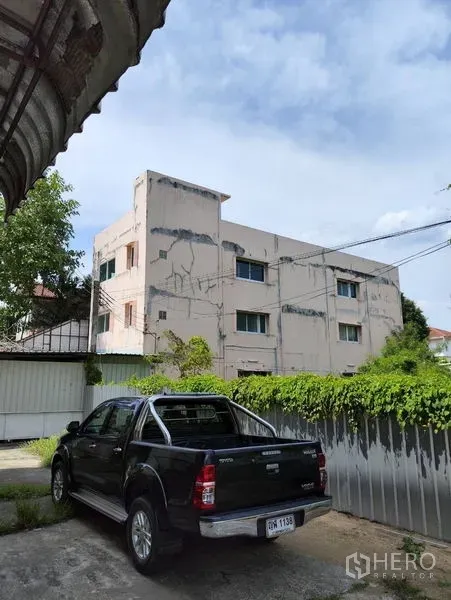 Warehouse for rent in Bueng Kum, Bangkok - Gated front yard with parking beside an industrial warehouse building.