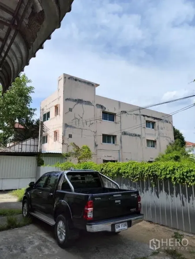 Warehouse for rent in Bueng Kum, Bangkok - Gated front yard with parking beside an industrial warehouse building.