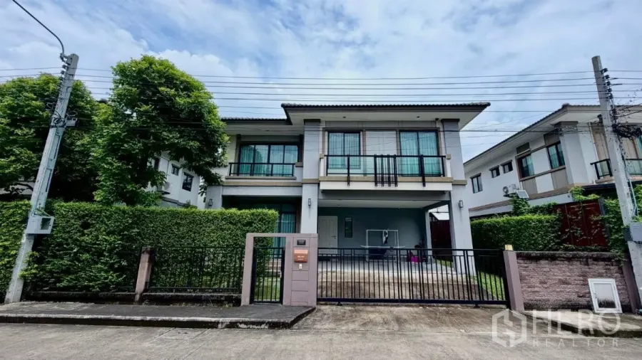 บ้าน ให้เช่าหรือขายในBang Phli, Samut Prakan - มุมมองหน้าบ้านเดี่ยว 2 ชั้น พร้อมรั้วและโรงจอดรถ มีแนวรั้วต้นไม้ในบางพลี