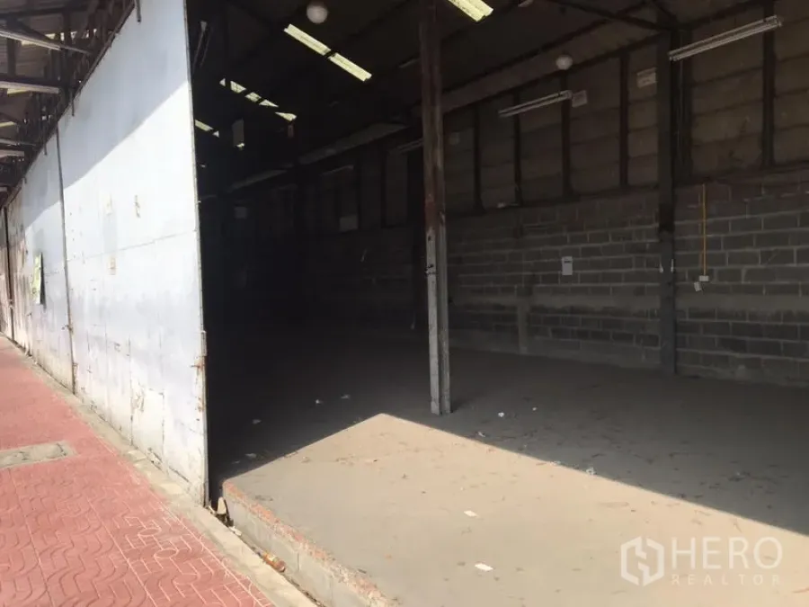 货栈 出租在Don Mueang, Bangkok - 开放式仓库车间，高挑屋顶、混凝土地面与砖墙，荧光灯照明，旁有红砖人行道，位于廊曼区。
