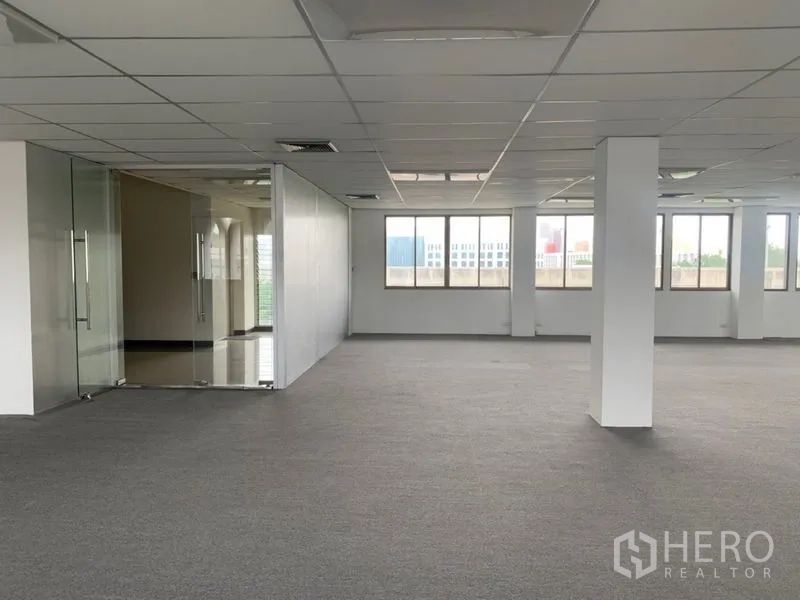 Office Space for rent in Ratchathewi, Bangkok - Bright open-plan office floor with carpet tiles, grid ceiling, and a glass-partitioned meeting room beside large windows.