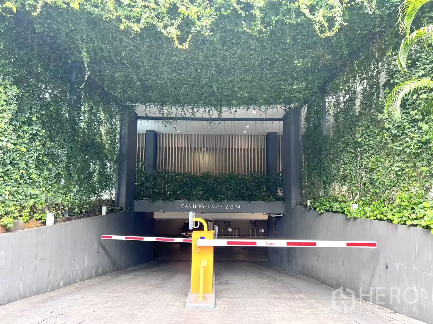 公寓 出售在Watthana, Bangkok - 公寓车道入口，设道闸与满墙绿色藤蔓。