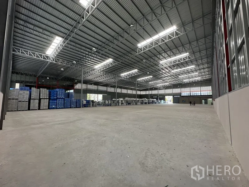 Factory for rent in Chachoengsao - Large industrial hall with stacked pallets, roof skylights and multiple loading points.