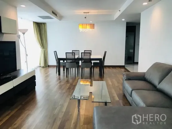 Condominium for rent in Pathum Wan, Bangkok - Open living and dining space with sofa set, glass table, chandelier and wide windows.