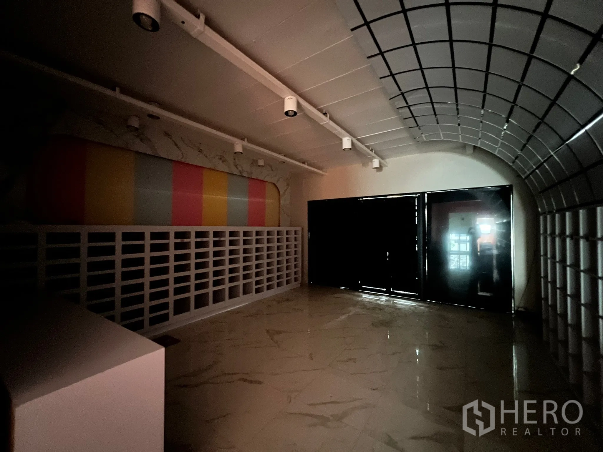 Shophouse for rent in Watthana, Bangkok - Dim showroom featuring an arched grid ceiling, glossy floors, and a colorful feature wall.