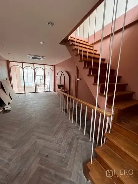 Shophouse for rent or sale in Watthana, Bangkok - Open-plan level featuring wooden staircase, herringbone flooring and full arched windows.