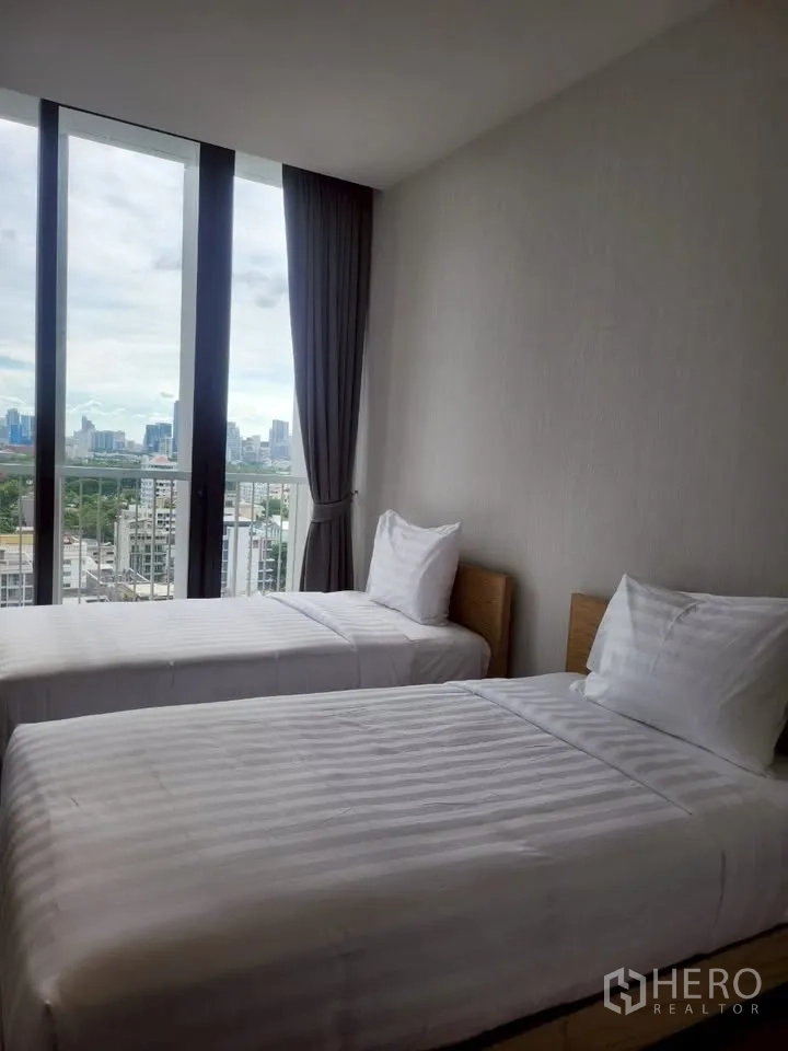 Condominium for rent in Khlong Toei, Bangkok - Second bedroom with two single beds, large windows and open city views.