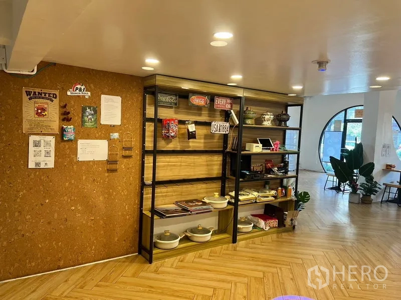 Shophouse for rent in Phra Khanong, Bangkok - Retail display shelving with warm lighting and a cork feature wall near the entrance.