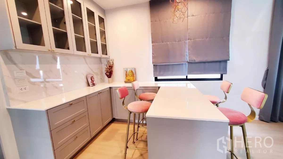 Detached House for rent in Lat Krabang, Bangkok - Pantry with white countertops, glass-front cabinets, island and pink bar stools under warm lighting.