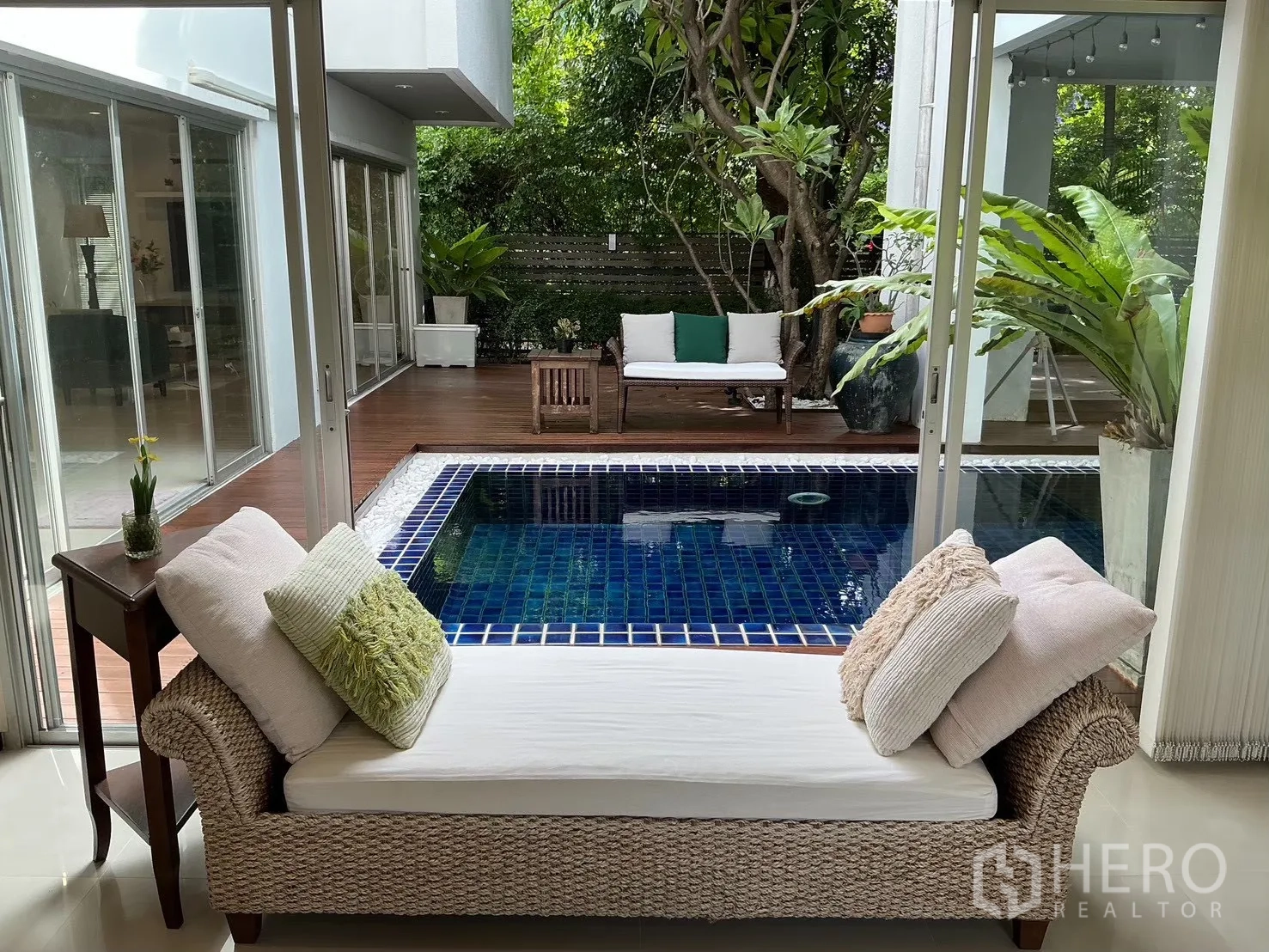 独栋房屋 for sale in Suan Luang, Bangkok - 室内休闲区面向蓝色马赛克私人泳池与木平台。