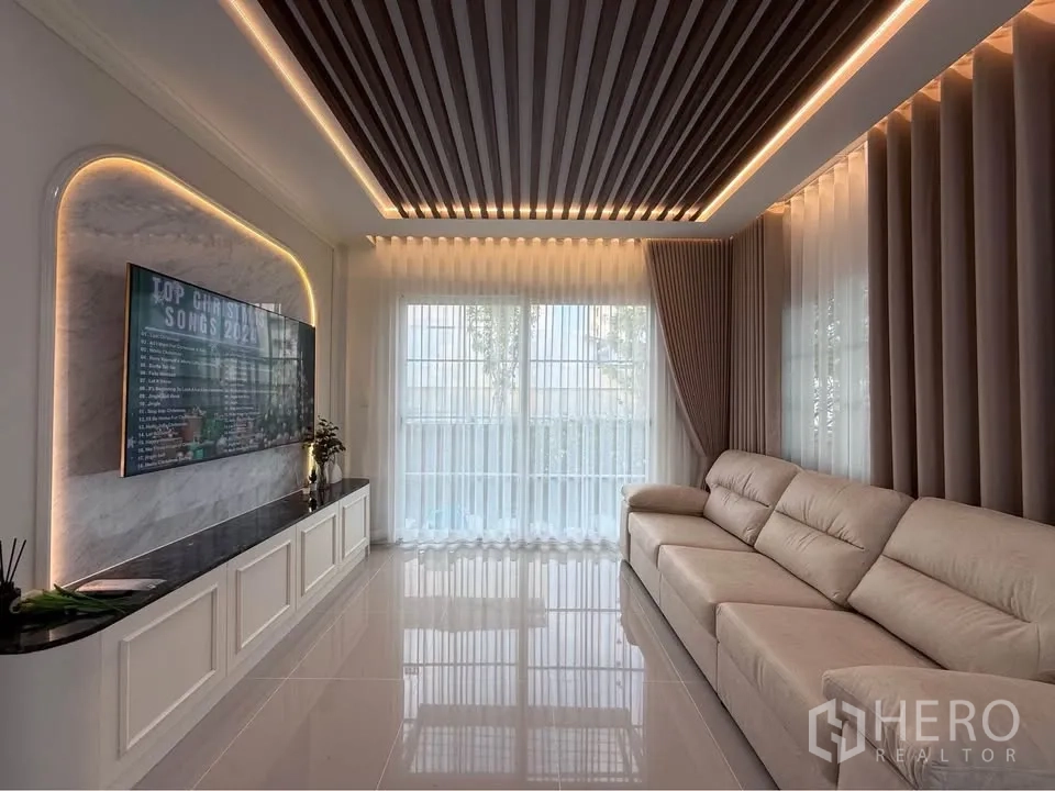 Semi-detached House for rent in Mueang Samut Prakan, Samut Prakan - Spacious living room with long sofa, TV wall, and LED ceiling lighting.
