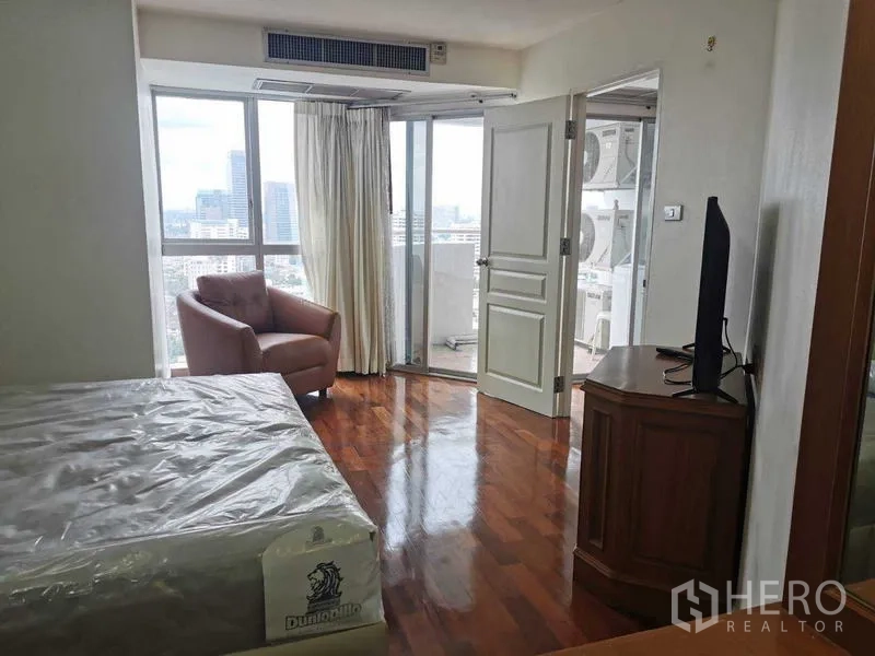 Condominium for rent - Bright bedroom with armchair and sliding doors to a balcony with city views.