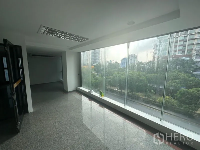 办公空间 出租在Sathon, Bangkok - 明亮走廊式办公区，宽幅玻璃景窗，可见树林与高楼景观。