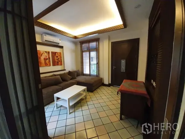 บ้าน ให้เช่าในWang Thonglang, Bangkok - ห้องนั่งเล่นปูกระเบื้อง โซฟารูปตัวแอล ฝ้าไฟซ่อน และบานหน้าต่างไม้บลายด์