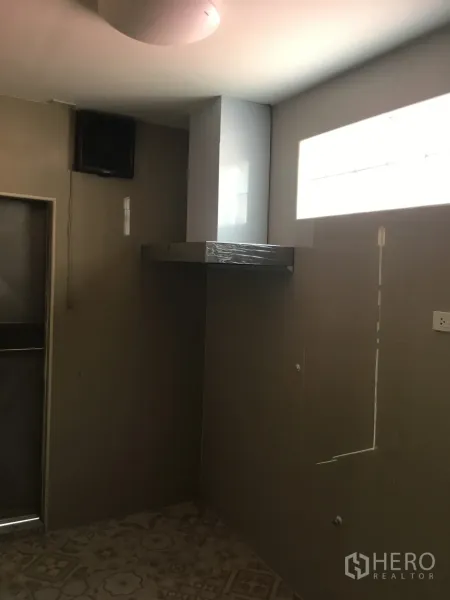Townhouse for rent in Huai Khwang, Bangkok - Simple Thai kitchen with tiled walls, ventilation hood and patterned floor tiles.