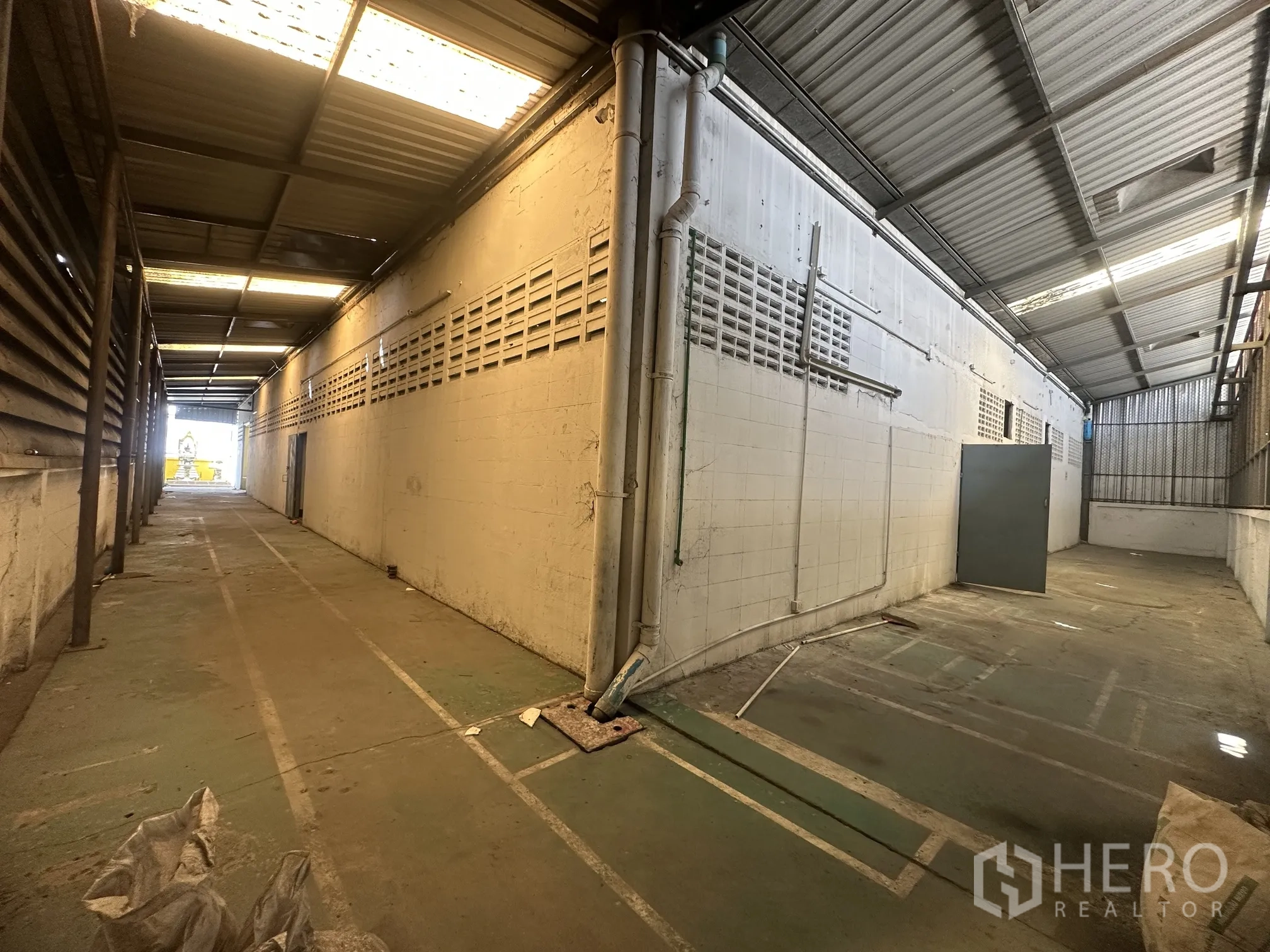 Factory for rent in Lat Lum Kaeo, Pathum Thani - Long covered side service lane with partial skylights and concrete flooring.