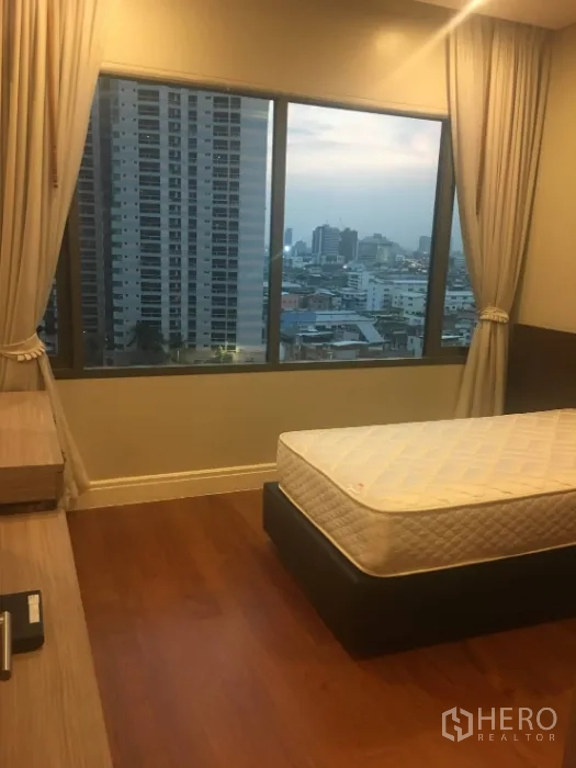 Condominium for rent in Khlong Toei, Bangkok - Bedroom with large window and skyline view, wood flooring and a single bed frame.
