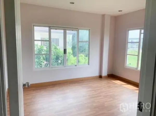 Detached House for sale in Saphan Sung, Bangkok - Bright empty bedroom with large sliding windows and wood floors overlooking greenery.