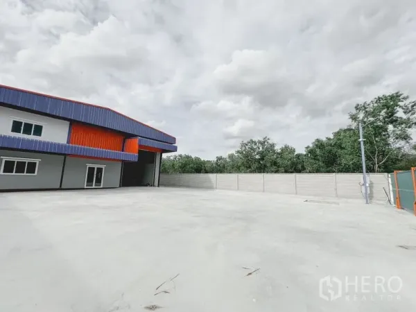 货栈 出租或出售在Khlong Luang, Pathum Thani - 仓库侧的大型混凝土堆场，高卷闸装卸口、围墙与绿化背景。
