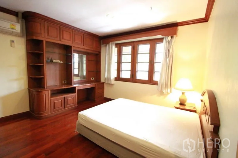 独立式住宅 出租在Prawet, Bangkok - 卧室带定制影音墙与书桌，三扇窗，实木地板亮丽。