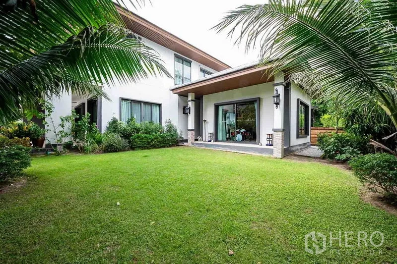 独立式住宅 出售在Prawet, Bangkok - 后花园草坪与有顶露台，落地推拉门连接室内。